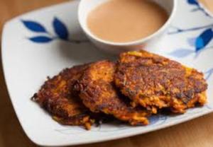 Potato pancakes with dipping sauce on plate.