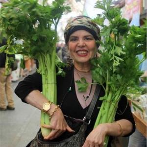 A woman holding two stalks of broccoli in her hands.