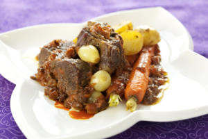 Braised beef with vegetables on white plate.