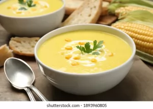 A bowl of soup with crackers and spoon.