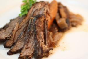 Sliced roast beef with garnish on plate.