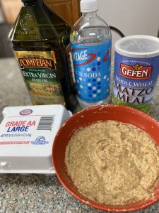 A bowl of food next to two cans and a bottle.