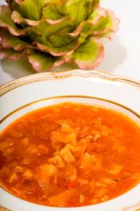 Soup in bowl with artichoke decoration.