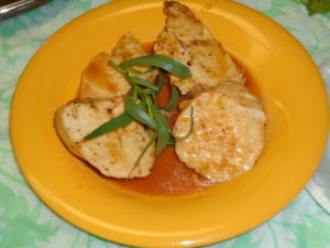 Grilled chicken with sauce on yellow plate.