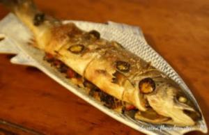 Baked fish with jalapeño on decorative platter.