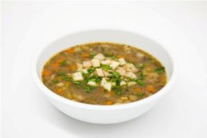 Bowl of vegetable soup with chopped herbs.