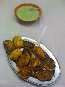 Fried patties with green dip on table.