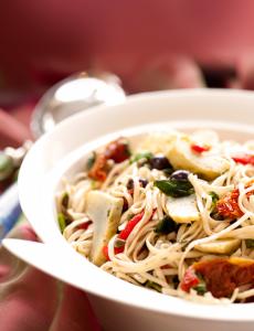 A bowl of pasta with vegetables and meat.