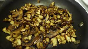 Sautéed mushrooms and onions in a pan.