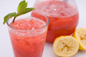 Red drink with lemon and mint garnish.