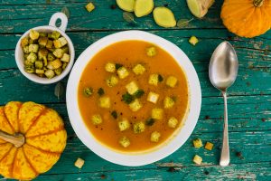 A bowl of soup with corn on the side.