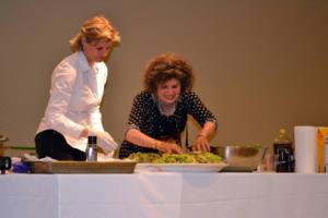 Two women are cutting vegetables on a table.
