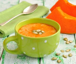 A cup of soup with pumpkin and nuts.