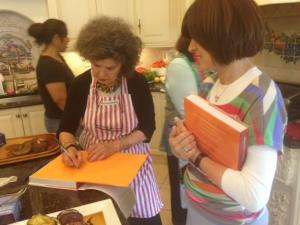 Woman autographing cookbook while others watch
