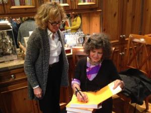 A woman sitting in front of another woman holding a pen.