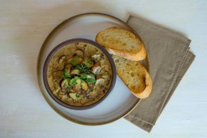 A bowl of soup and two pieces of bread.