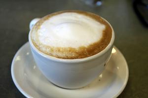 A cup of coffee with cream on top.