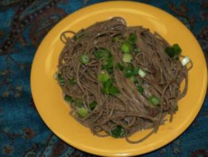 Soba noodles with green onions on plate.