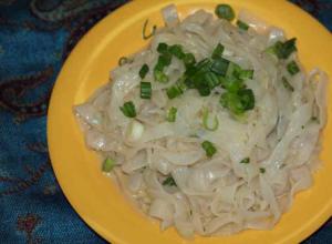 Noodles with green onions on yellow plate.