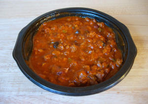 Bowl of hearty chili on wooden table.