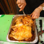 Person carving roasted chicken in a tray.