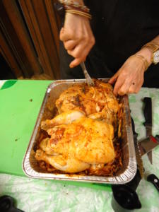 Person carving roasted chickens in a tray.