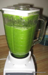Blender with green smoothie on countertop.
