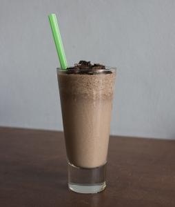 A glass of chocolate milk with a green straw.