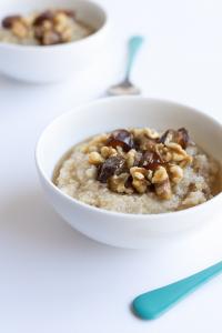 A bowl of oatmeal with nuts on top.