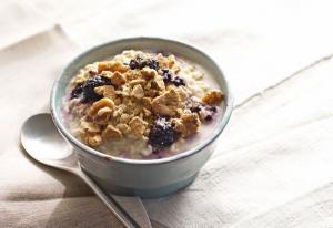 A bowl of cereal with blueberries and nuts.
