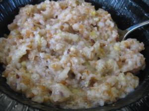 Bowl of cooked buckwheat porridge with spoon.