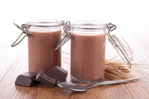 Two jars of chocolate pudding with spoons and a spoon.