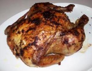 Roasted whole chicken on a white plate.