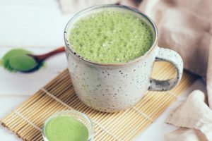 A cup of green tea sitting on top of a wooden table.