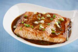 Grilled salmon with sauce and green onions.