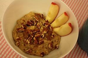 Bowl of oatmeal with pecans and apples.