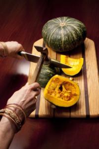 Cutting green squash on wooden board.