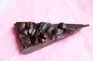 A piece of chocolate sitting on top of a pink surface.
