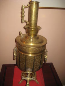 Ornate brass samovar on wooden table.