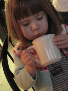 Child sipping from a white mug.