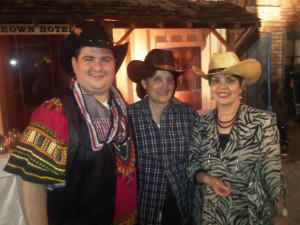 Three people in cowboy hats smiling together.