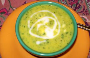 Green soup with cream swirl in bowl.