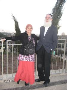 Elderly couple posing outdoors near railing.