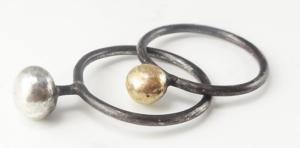 A gold bead is sitting on top of two black rings.