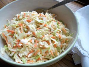 A bowl of coleslaw with carrots and cabbage.