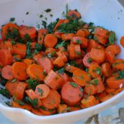 A bowl of carrots and greens on the table.