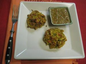 Zucchini fritters with sauce on square plate.