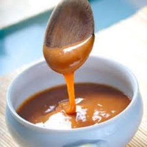 Caramel sauce dripping from wooden spoon.