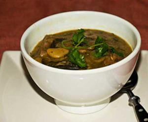 Bowl of soup with herbs and spoon.
