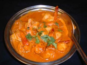 A bowl of curry with shrimp and cilantro.